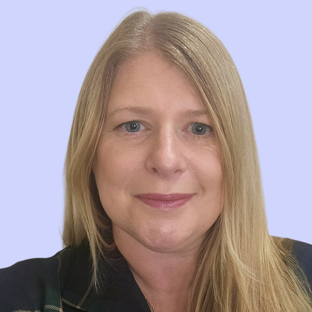 Jeannie Bennett smiles for a photo on a light purple background